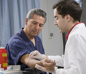 Proveedor de atención médica que extrae sangre del brazo de un hombre.