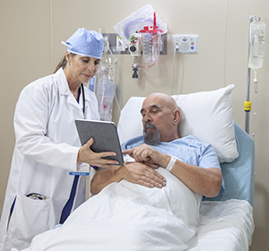 Proveedor de atención médica hablando con un hombre en la sala preoperatoria del hospital.