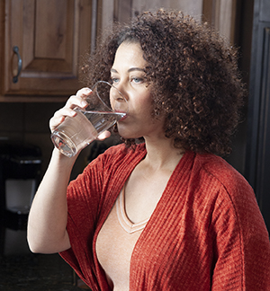 Mujer que bebe un vaso de agua.