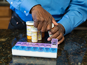 Hombre llenando un pastillero con medicamentos.